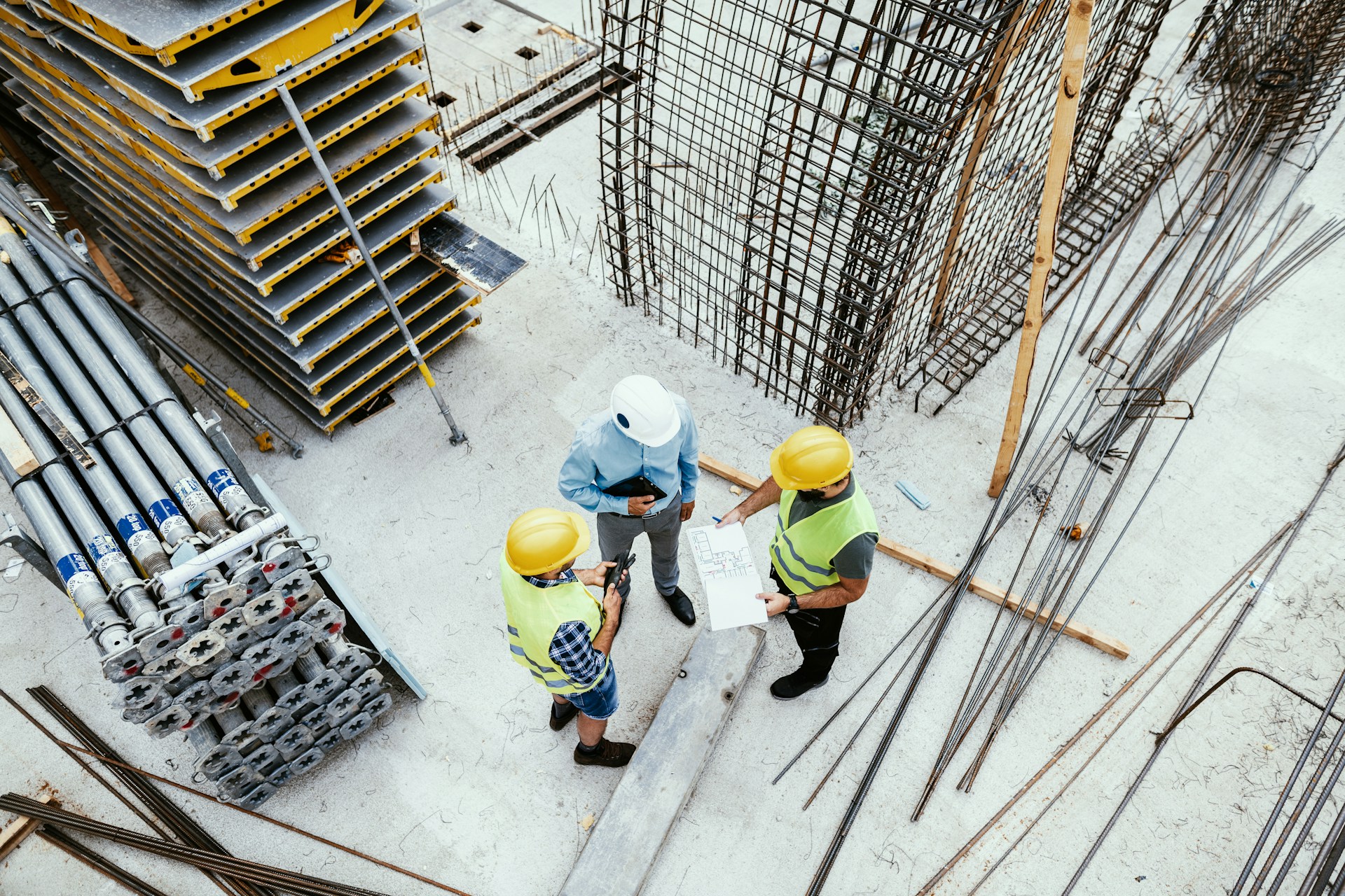 Three people standing together in the midst of large collections of construction equipment