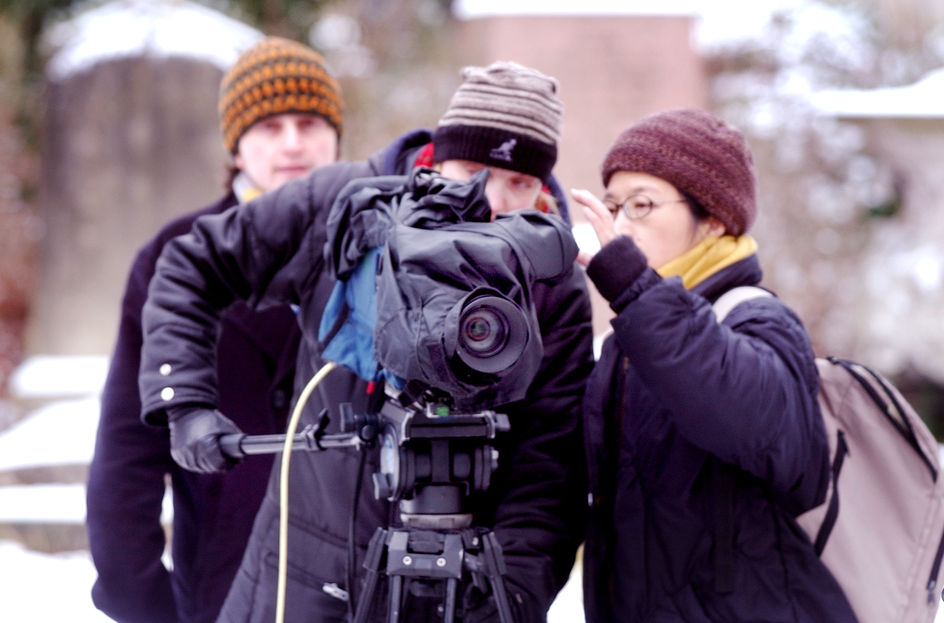Three apprentices on location behind a camera