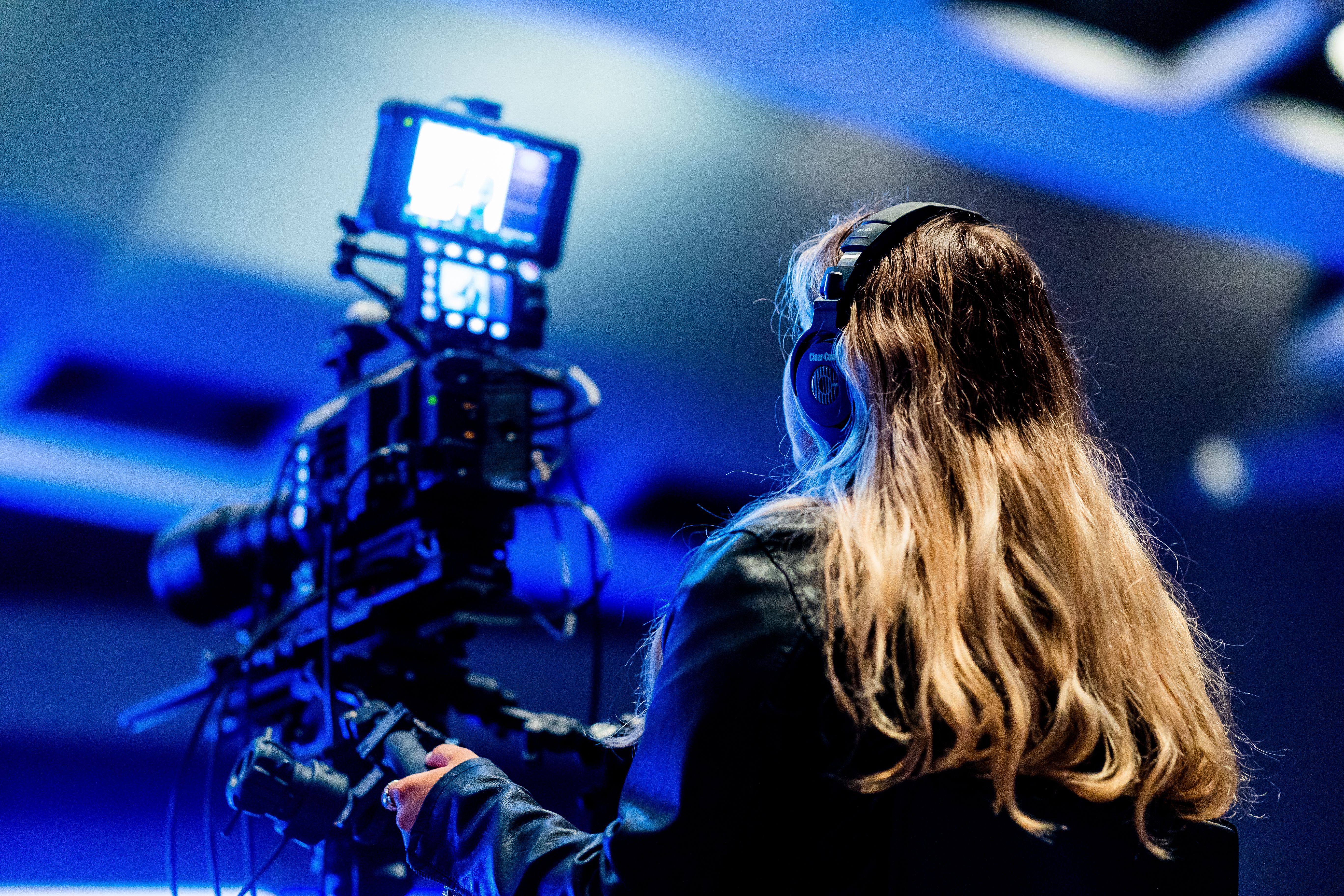 A camera operator records an indoor event in low blue lighting