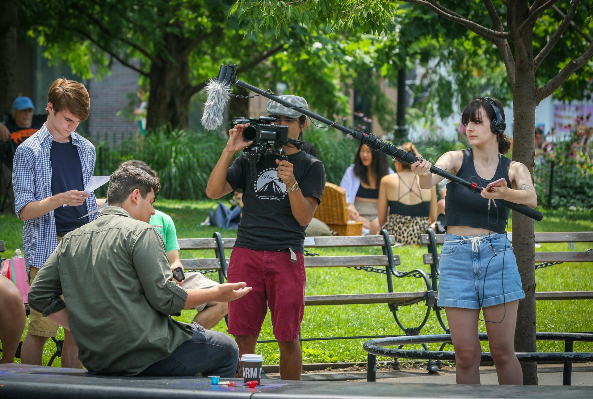 Camera and sound crew filming a person sat on a park bench 
