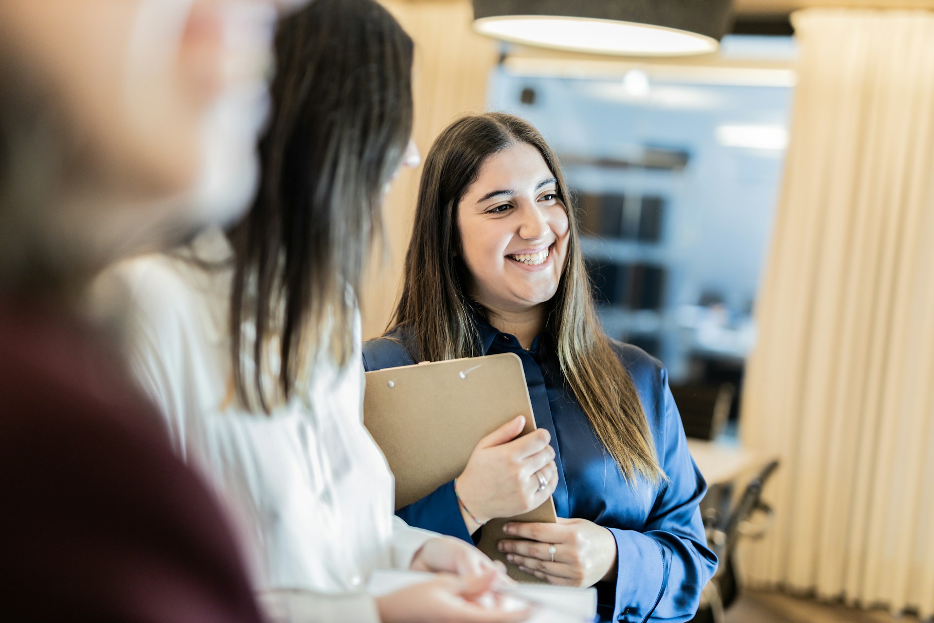 A photo of a woman smiling and holding a clipboard.
