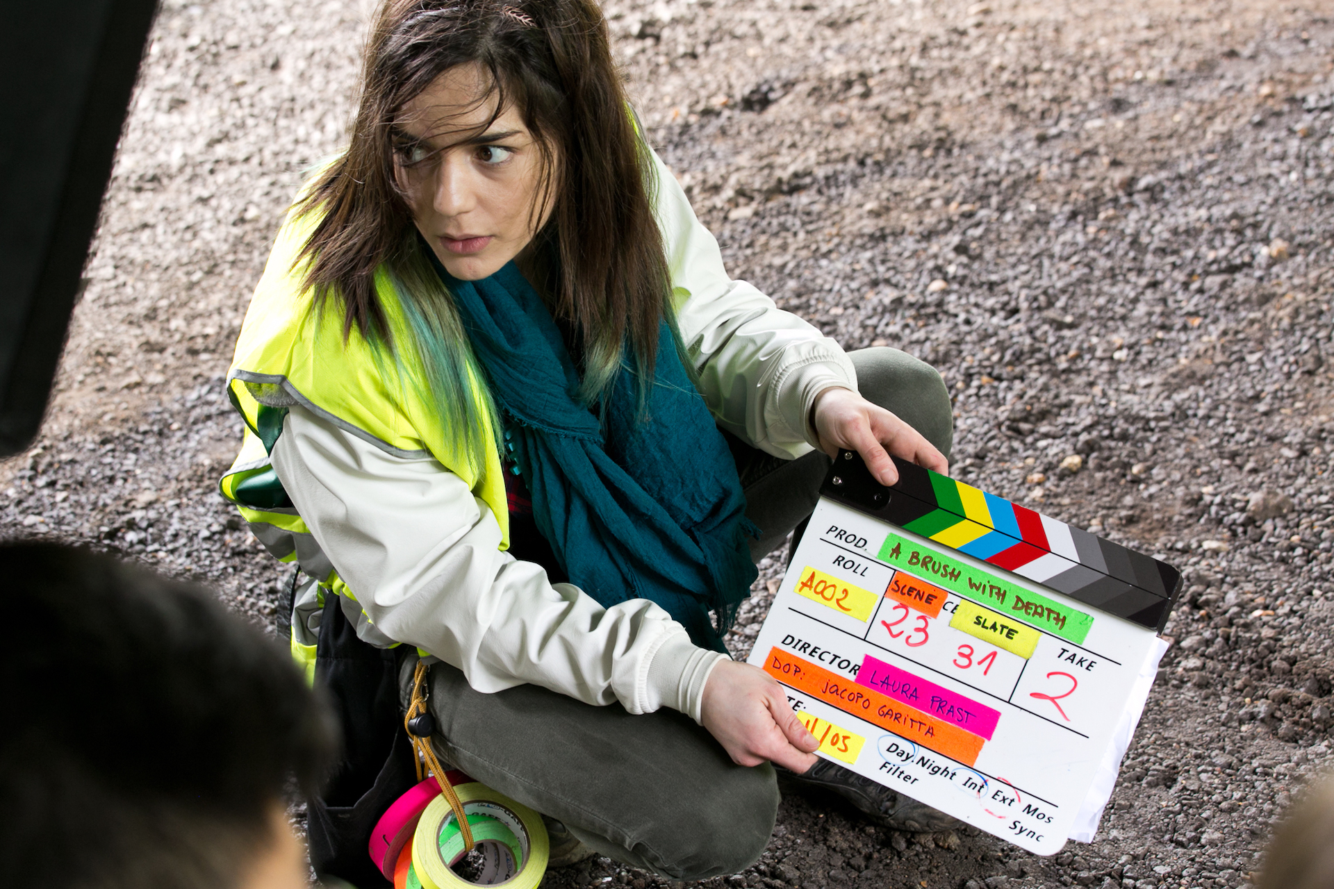 Woman crouching on the ground with a clapper board