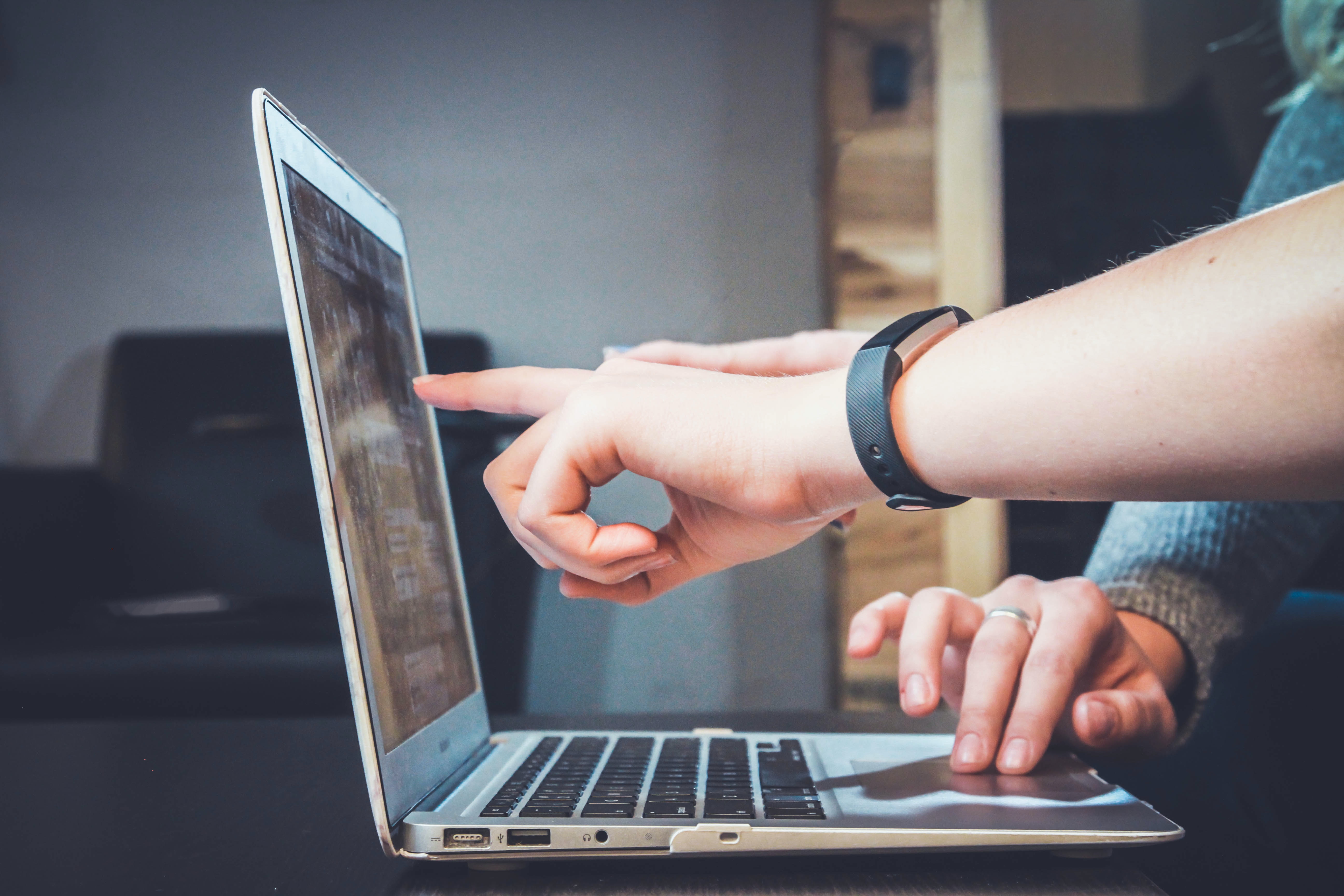 Hand pointing to laptop screen