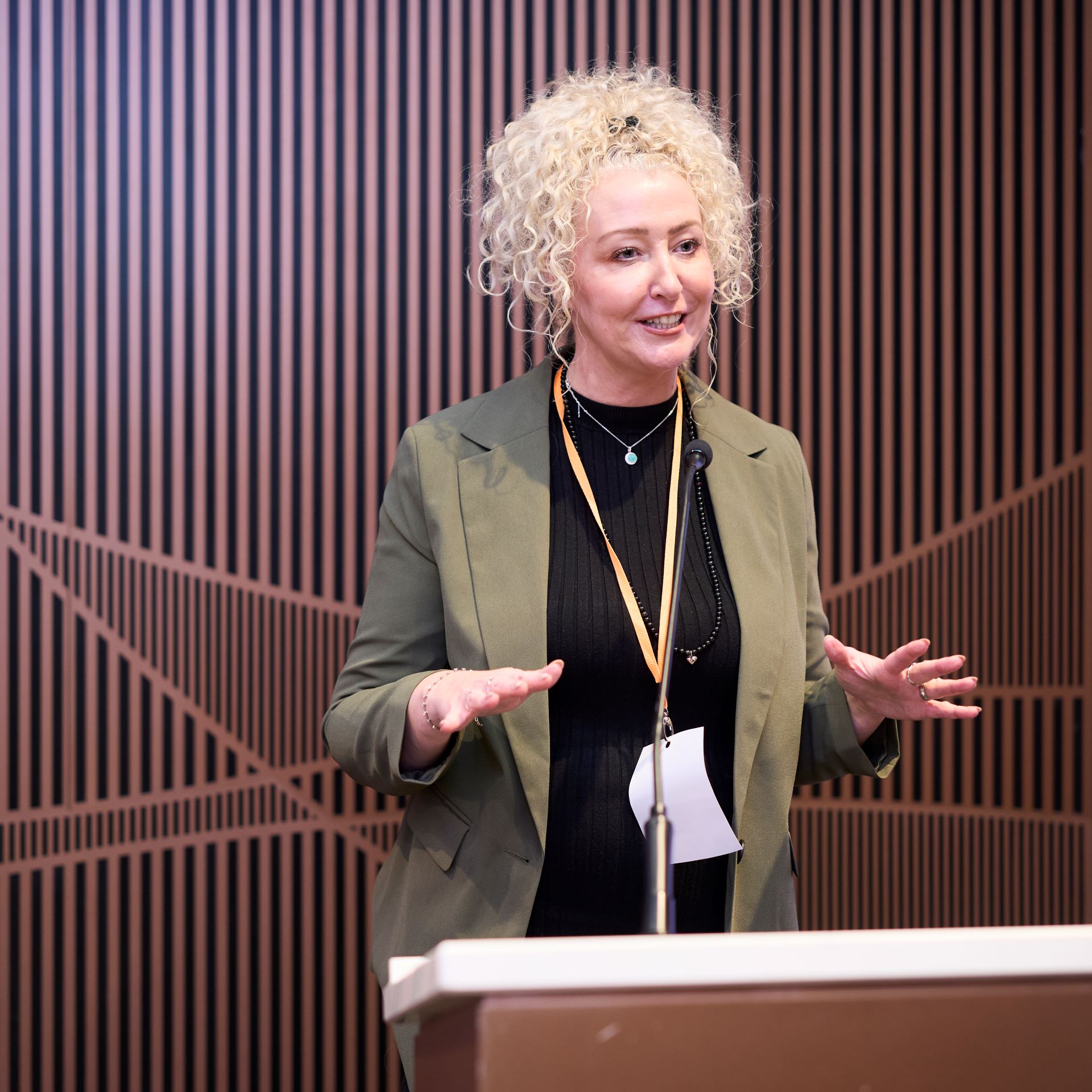 Hair and make-up artist Melanie Doyle stands at a podium giving a presentation