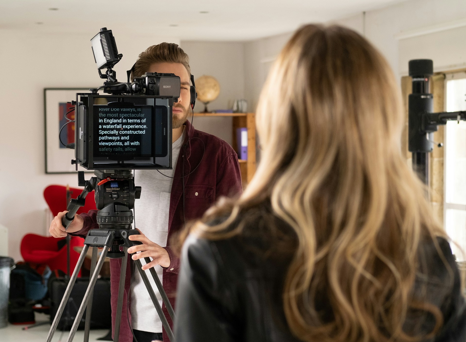 A person speaks to a camera, reading from an autocue teleprompter