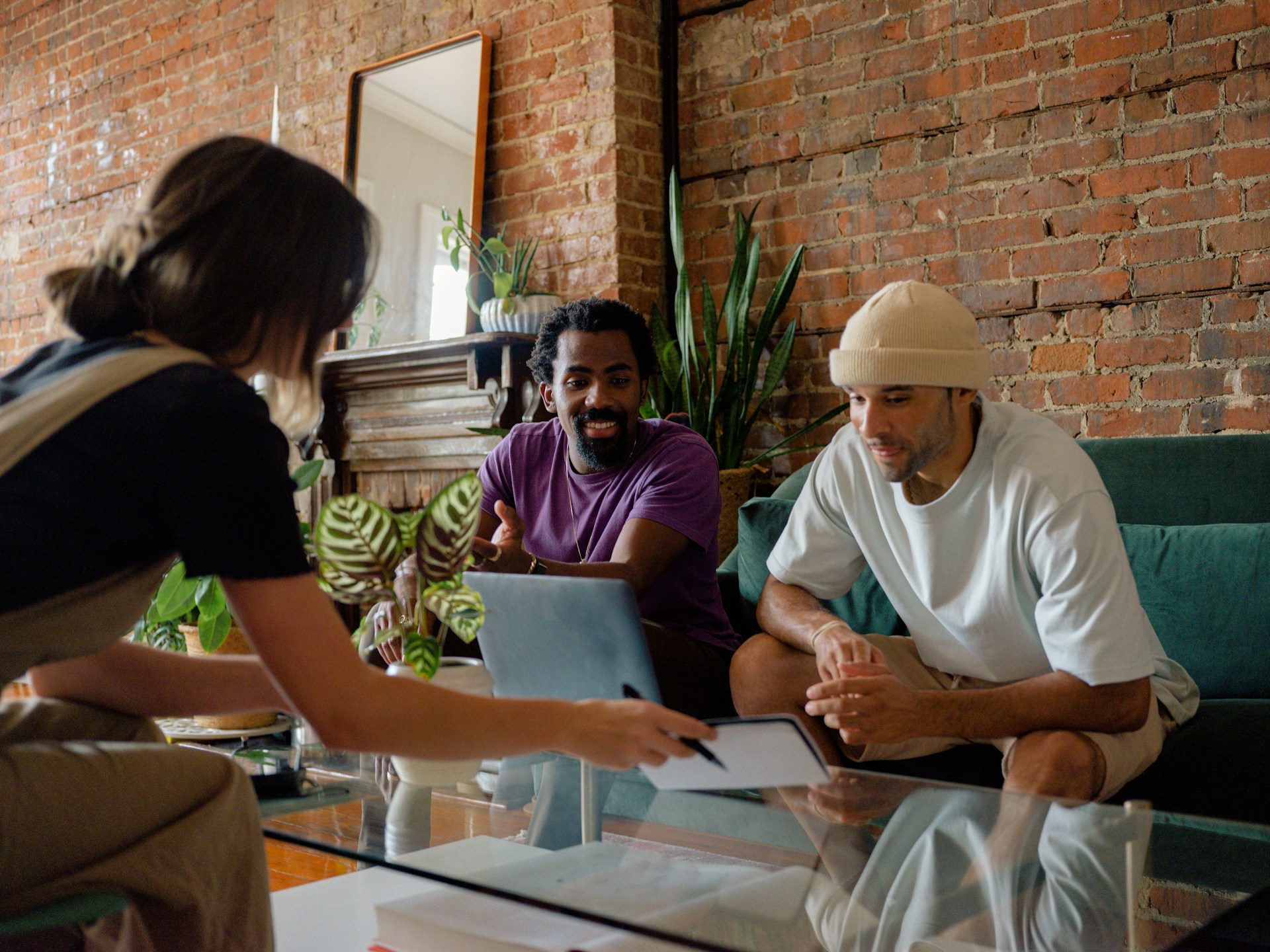 Three people sit around a table looking at a laptop screen