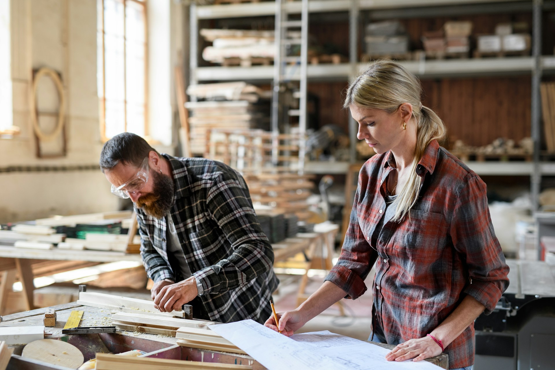 Two carpenters working side by side in a workshop.