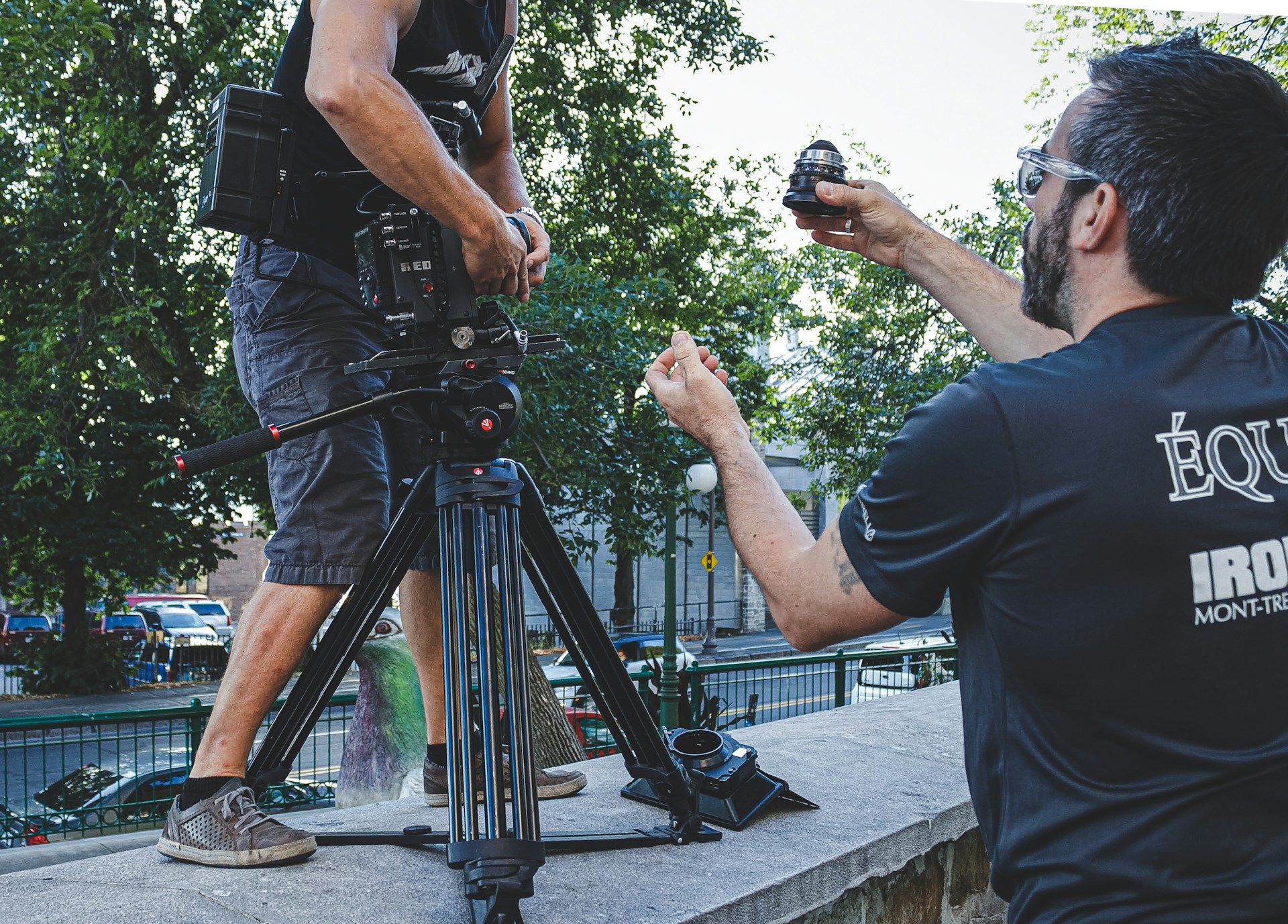 A camera assistant passes a camera lens to a camera operator