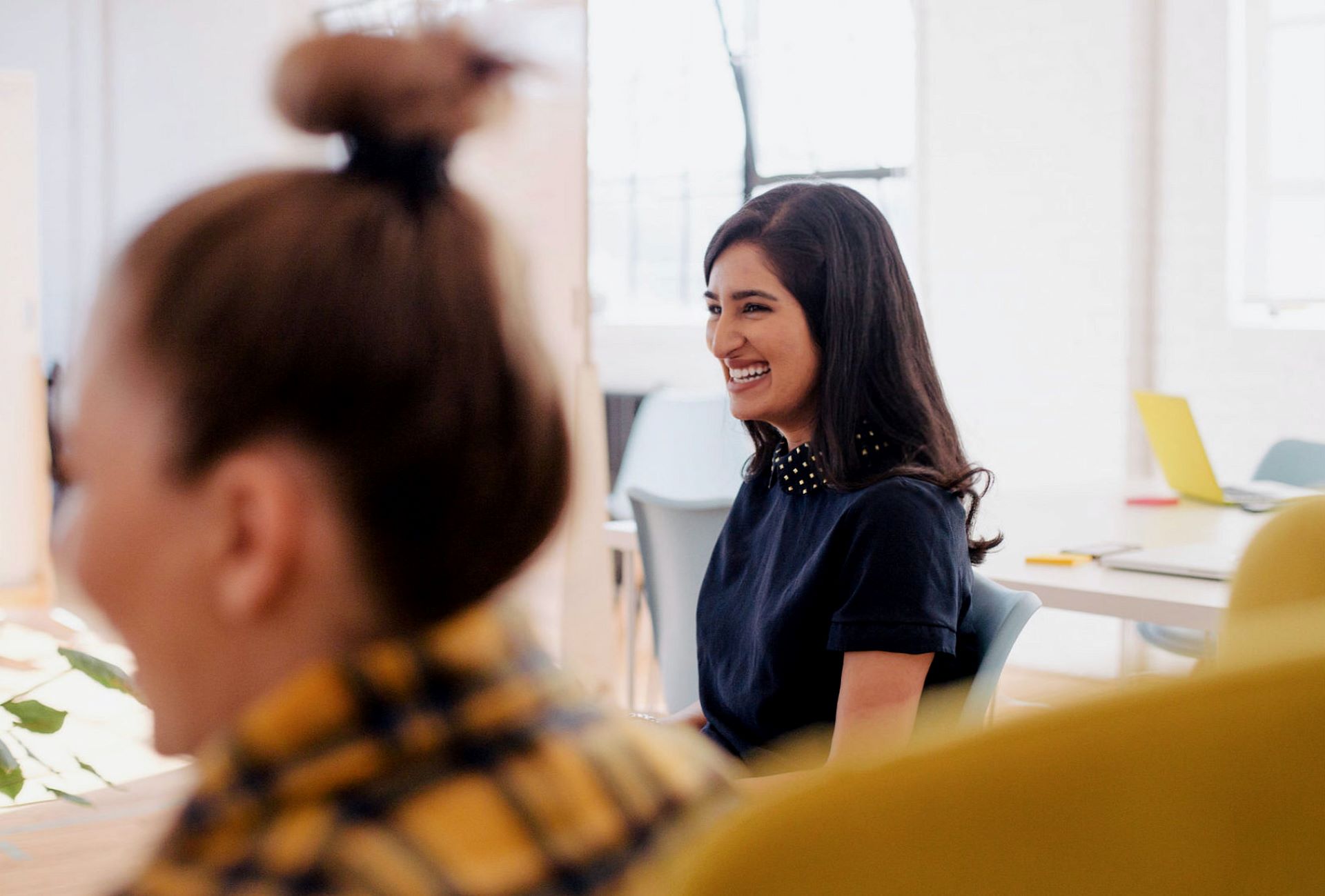 Two people are sat at a desk smiling