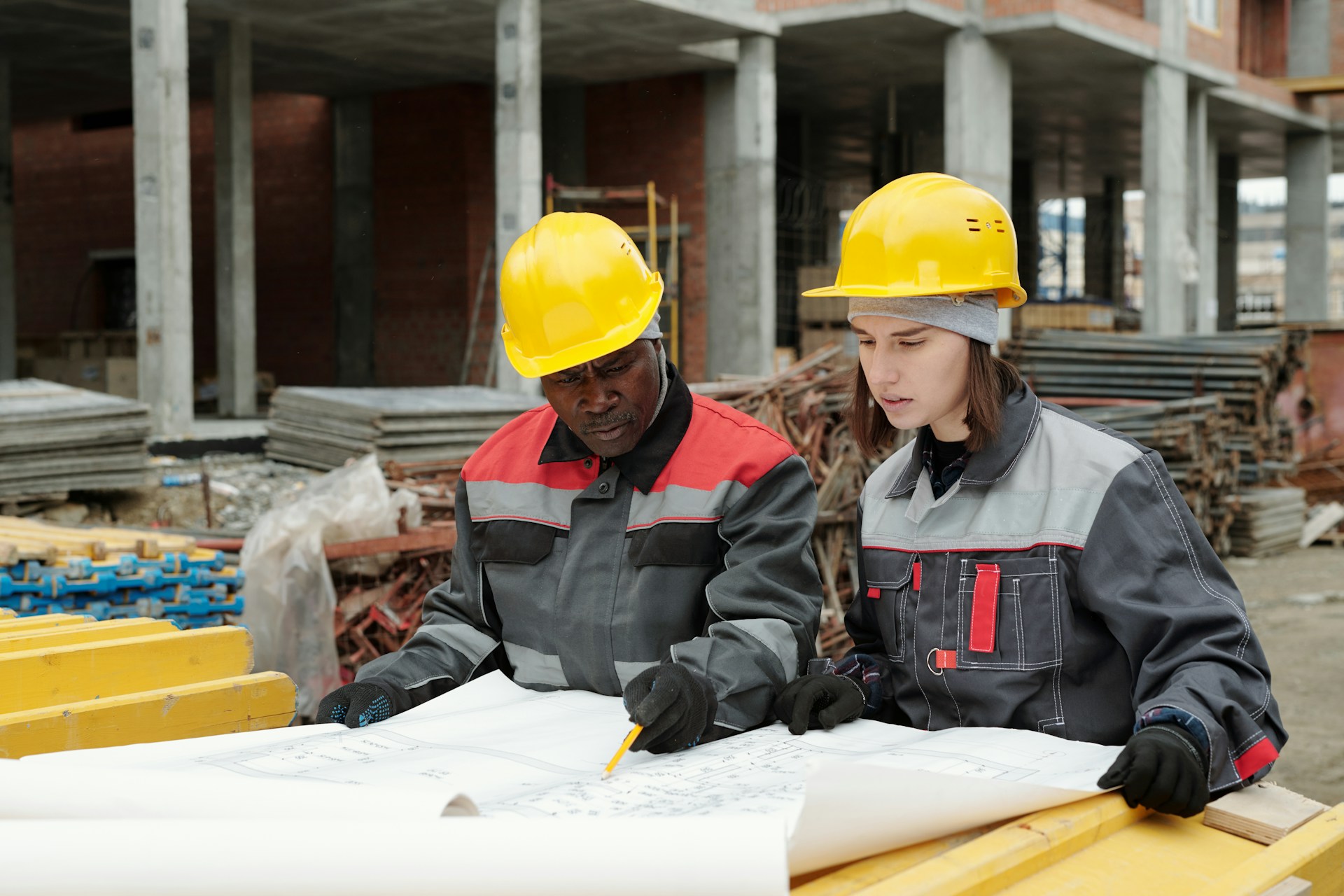Two construction workers standing together and looking at construction plans