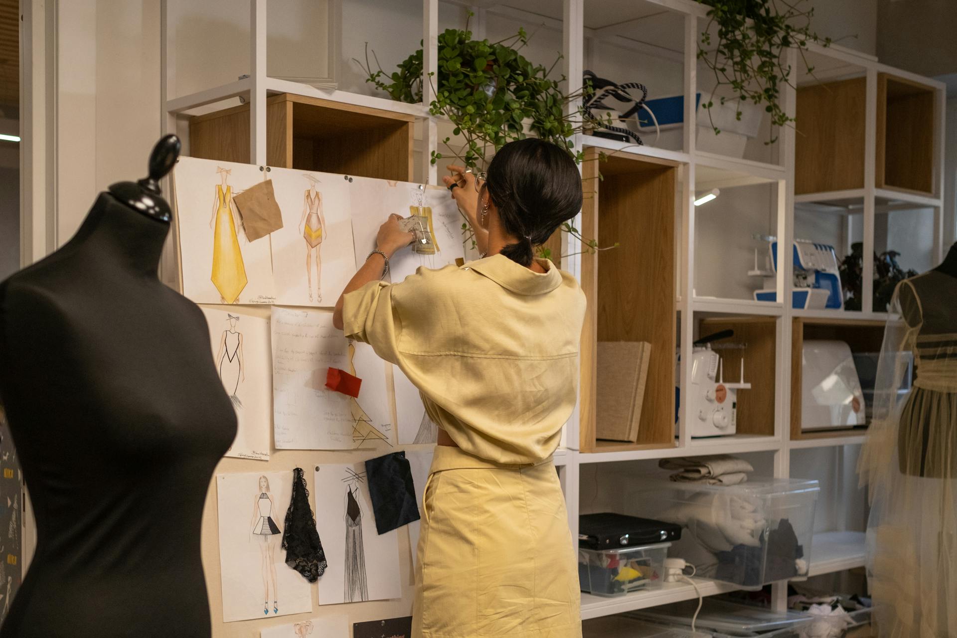 A person in a sewing studio pins some fabric to a design pin board 
