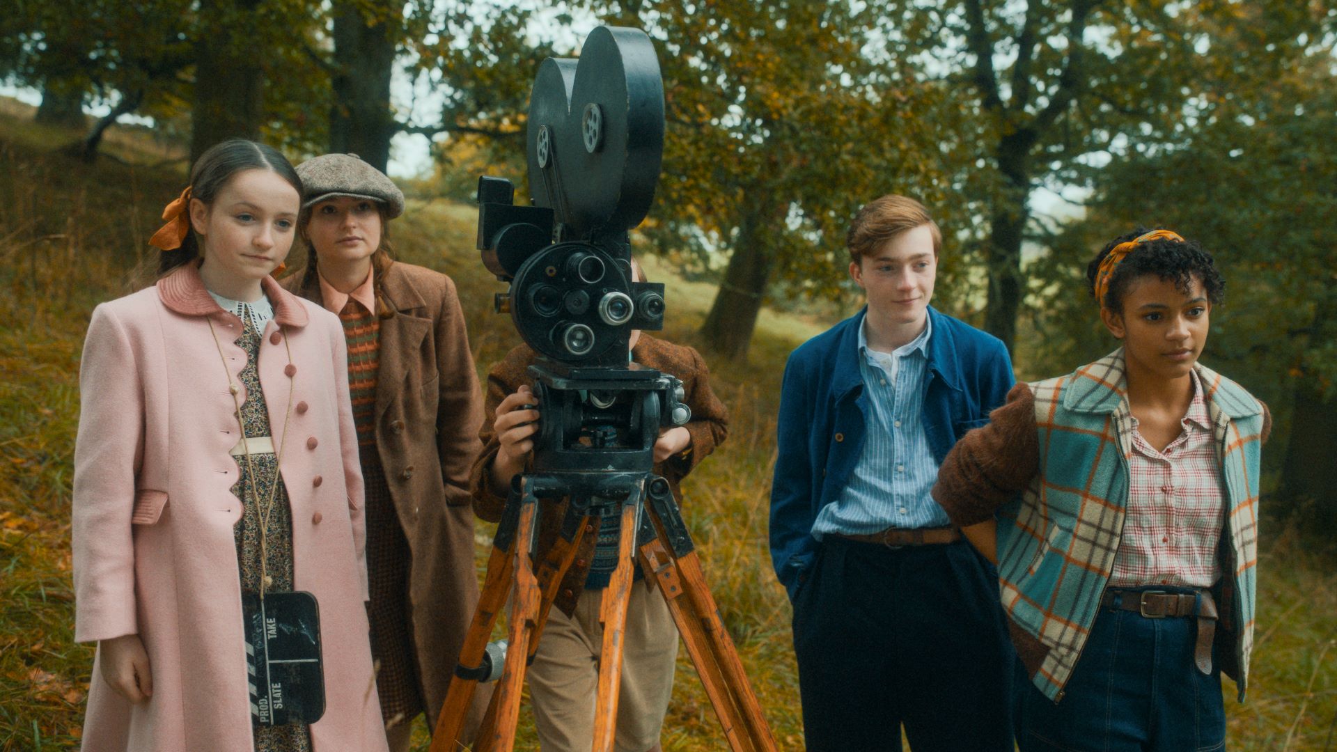 Five children stand around an old cinema camera.