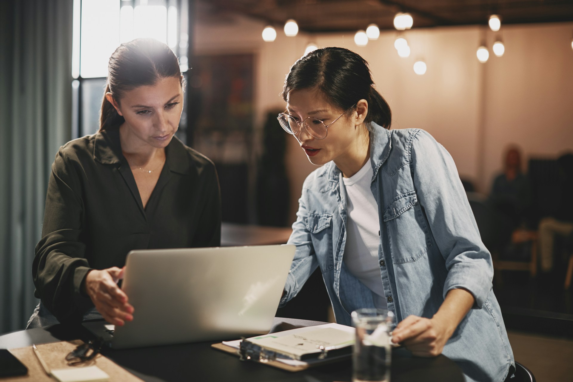 Two women sit together looking at a laptop screen